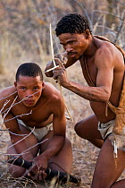 Kalahari bushmen, Qhaikgao (right) teaching Xamse (left) how to hunt with a bow and arrow, Central Kalahari Desert, Botswana, August 2008