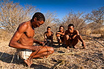 Kalahari bushmen, huntsman showing other how to make rope from natural plant fibers, Central Kalahari Desert, Botswana, August 2008