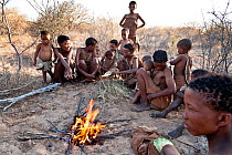 Kalahari bushmen, family sitting round fire in the bush. Central Kalahari Desert, Botswana, August 2008