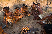 Kalahari bushmen, family sitting round fire in the bush, dry season, Central Kalahari Desert, Botswana, August 2008