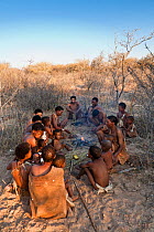 Kalahari bushmen, family sitting round fire in the bush, dry season, Central Kalahari Desert, Botswana, August 2008