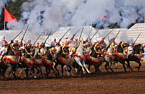 Traditionally dressed Berber warriors, mounted on Barb and Arab Barb horses, galloping in formation, firing guns during the Fantasia in Dar Es Salam, Morocco, June 2010