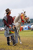A Khampa warrior walks with his Tibetan stallion during the horse festival, near Huangyan, in the Garze Tibetan Autonomous Prefecture, Sichuan Province, China, June 2010
