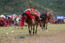 Two Khampa warriors, mounted on their running Tibetan horse, try to catch sweets laid out on the ground, during the horse festival, near Huangyan, in the Garze Tibetan Autonomous Prefecture in the Sic...