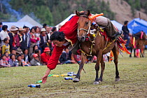 A Khampa warrior, mounted on his running Tibetan horse, tries to catch sweets laid out on the ground, during the horse festival, near Huangyan, in the Garze Tibetan Autonomous Prefecture in the Sichua...