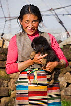 A Khampa woman farmer holds a baby Tibetan Mastiff, near Huangyan, in the Garze Tibetan Autonomous Prefecture in the Sichuan Province, China, June 2010