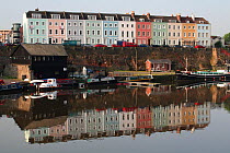 Terrace of colourful houses on Redcliffe Quay, reflected in the water of Bristol's floating Harbour in early morning, Bristol, England, May 2008.