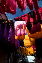 Skeins of wool and clothing hanging up to dry in the dye souk, Marrakech, Morocco, March 2010.