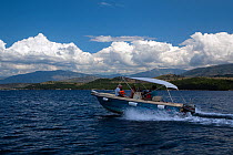 Motorboat with family aboard cruising off the north-east coast of Corfu, with the coast of Albania in the background, Corfu, Greece, June 2010. Model released.
