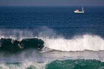 Surfer on a wave in Booby's Bay with boat beyond, Cornwall, England, August 2010.
