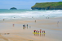 Surf school practising balancing on surf boards on the beach before entering the sea. Polzeath, north Cornwall, UK, April 2010.