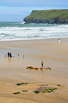 Surf school practising surf board paddling technique, before entering the sea. Polzeath, north Cornwall, UK, April 2010.