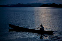 Man from Waifoy Village paddling a canoe at night off the coast of Waigeo Island, West Papua, Indonesia, April 2007