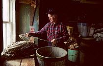 Man checking tub of longline fishing equipment. Francois, Newfoundland, Canada, 1992.