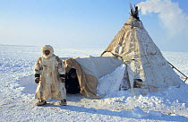 Tundra Nenets man outside a winter reindeer skin tent on the tundra. Gydan Peninsula, Western Siberia, Russia, 2000.
