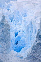 Crevasse leading deep into glacier revealing ice bridges and cold blue shadows. Cierva Cove, Antarctica, February 2009.