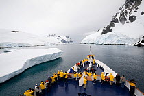 Ice breaker "Clipper Adventurer" passing an iceberg in the Lemaire Channel on a grey day, Antarctica, February 2009.
