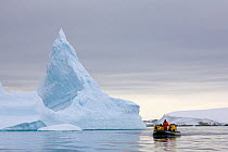 Zodiac filled with tourists passing icebergs near to the Pleneau Islands, Antarctica, February 2009.