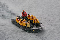 Zodiac filled with tourists powering through frazil ice in extreme weather, Stromness, South Georgia, 2009.