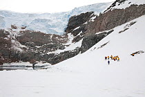 Tourists on the shore under a glacier on the Whittle Peninsula, Antarctic Peninsula, 2009.
