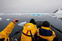 Tourists with cameras on board zodiac, Whittle Peninsula, Antarctica, 2009.