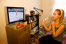 Young Chukchi woman playing Wii video game at her home in Anadyr. Chukotka, Siberia, Russia,  2010