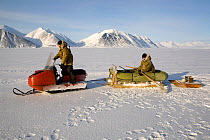 Yupik Eskimo hunters travelling to the floe edge by snowmobile with an inflatable boat. Tkachen Bay, Chukotskiy Peninsula, Chukotka, Siberia, Russia, 2010