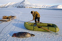 Yupik Eskimo hunter using inflatable boat to retrieve Ringed seal (Phoca Hispida) shot at the floe edge in Tkachen Bay. Chukotskiy Peninsula, Chukotka, Siberia, Russia, 2010