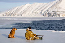 Yupik Eskimo hunter seal hunting with his dog (Canis familiaris) at the floe edge in Tkachen Bay. Chukotskiy Peninsula, Chukotka, Siberia, Russia, 2010