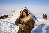 Chukchi woman using an Iridium Satellite phone at reindeer herders' winter camp. Chukotskiy Peninsula, Chukotka, Siberia, Russia, spring 2010