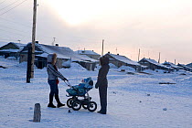 Two young Chukchi women with pram talking in the street. Neshkan, Chukotskiy Peninsula, Chukotka, Siberia, Russia, spring 2010