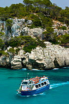 Tourist boat passing the Rocky coast of Cala Macarella, Menorca, Balearic Islands, Spain, Mediterranean, July 2005
