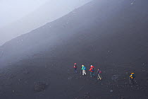 Hikers climbing Mount Etna in the mist, Etna, Sicily, Italy, October 2007