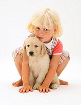 Portrait of young blonde haired girl sitting with Golden Retriever puppy. Model released