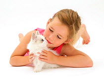 Portrait of a young girl lying down, playing with a kitten. Model released