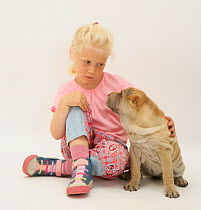 Portrait of young blonde haired girl sitting with a Shar-pei puppy Model released