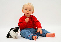 Portrait of toddler playing with black-and-white kitten using catnip mouse toy. Model released