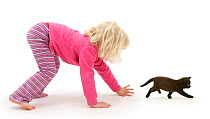 Young blonde haired girl chasing a black kitten. Model released