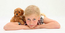 Portrait of young girl, lying down, with Cockerpoo (Cocker spaniel x Poodle) puppy, aged 7 weeks. Model released