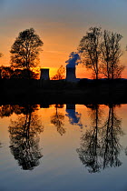 Silhouette of the Cattenom nuclear power station at sunset, reflected in the Moselle river, Lorraine, France, April 2009