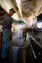 Man making syrup in his sugar house at the Sunday Mountain Maple Farm, Orford, New Hampshire, USA. March 2007