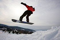 Snowboarder leaping into the air, Quechee Ski Hill, Quechee, Vermont, USA. February 2007