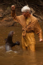 Diane McTurk with a Giant otter (Pteronura brasiliensis) leaping up for food, habituated, Karanambu Otter Trust for re-introduction, Rupununi, Guyana, Endangered species, August 2009