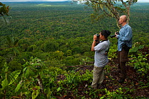 Man and woman photographing rainforest from Turtle Mountain, Iwokrama Forest Reserve, Guyana, January 2010