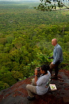 Man and woman birdwatching in the rainforest from Turtle Mountain, Iwokrama Forest Reserve, Guyana, January 2010