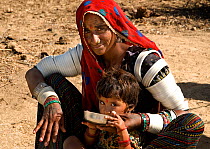 Maldhari woman with child drinking from bowl, Kutch, Gujarat, India, April 2009