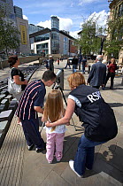 Young family looking through telescope at peregrine falcons as part of RSPB Peregrine Watch. Manchester, England, May.