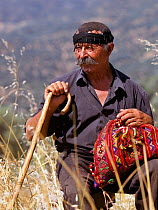 Portrait of Shepherd wearing traditional mandili head scraf, purse, and oak crook, Crete, Greece.