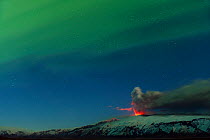 Ash plume and lava eruption from the Eyjafjallajokull volcano at night, with the Northern lights visible in the sky above, Iceland, April 2010