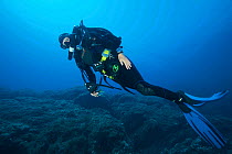 Rebreather diver swimming along the sea bed. Capraia, Tuscany, Italy, August. Model released.